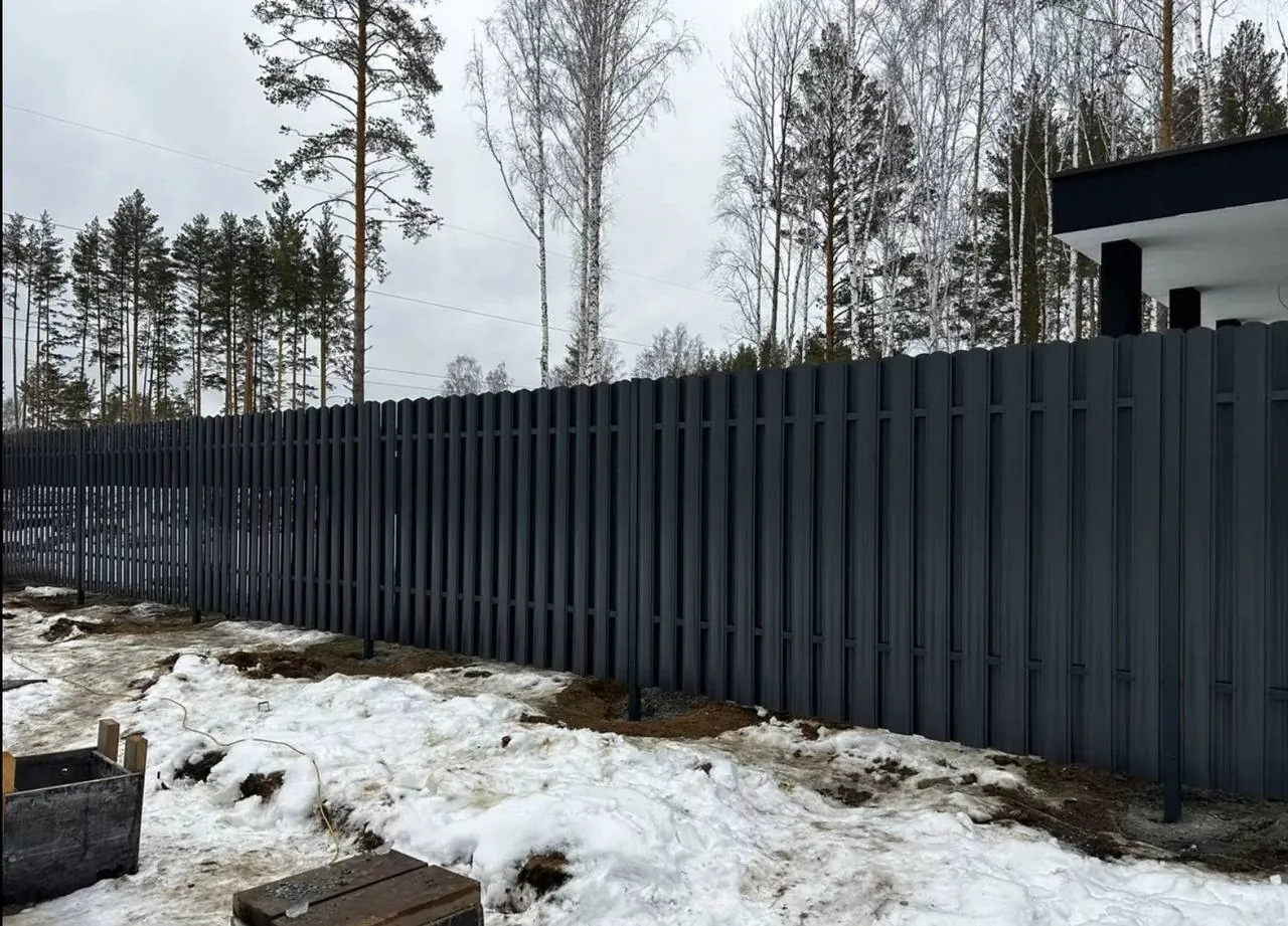Забор из евроштакетника Бархат графит RAL 7024 с калиткой зимой в Новосибирске